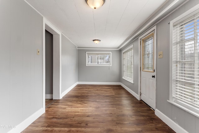 foyer entrance with dark wood-style floors, baseboards, and ornamental molding