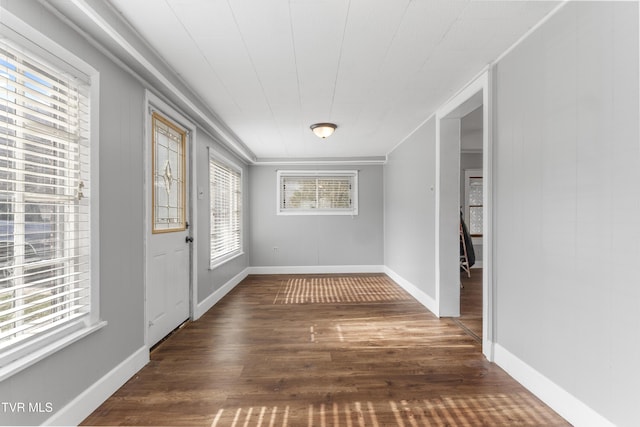 interior space featuring crown molding, baseboards, and wood finished floors