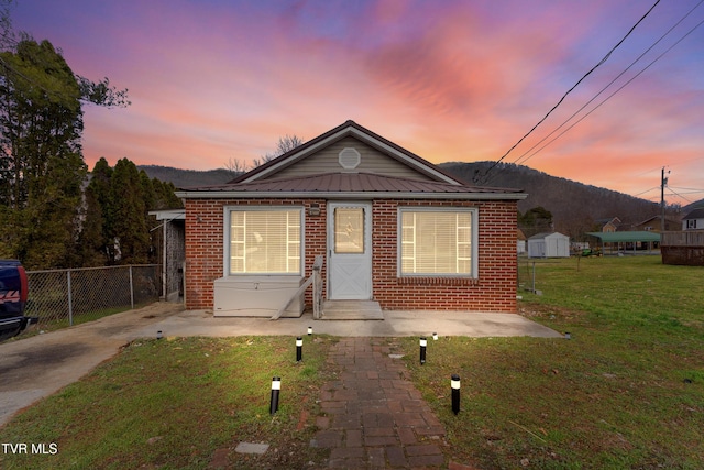 bungalow featuring a front yard, brick siding, fence, and a mountain view