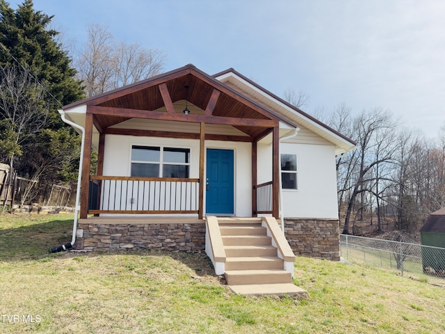 view of front facade with stucco siding, a porch, a front yard, and fence