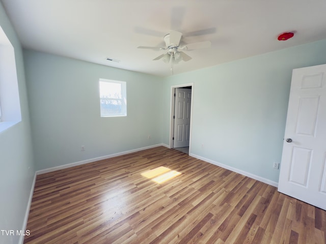 unfurnished bedroom featuring visible vents, ceiling fan, baseboards, and wood finished floors