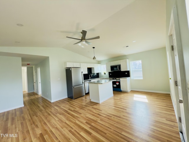 kitchen featuring a kitchen island, open floor plan, appliances with stainless steel finishes, light wood-style floors, and white cabinets