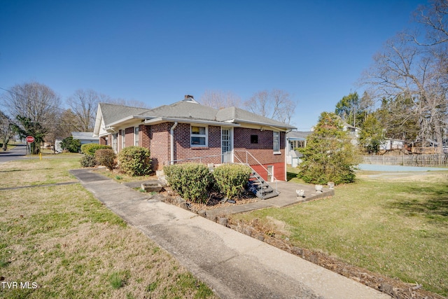 view of front facade featuring brick siding, a chimney, and a front yard