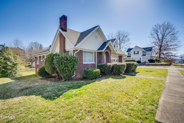 view of side of home featuring a shingled roof, a lawn, brick siding, and a chimney