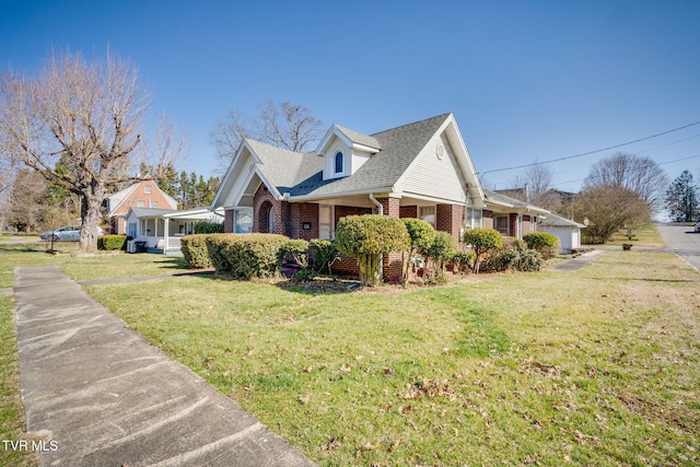 view of home's exterior featuring a lawn, brick siding, and a shingled roof