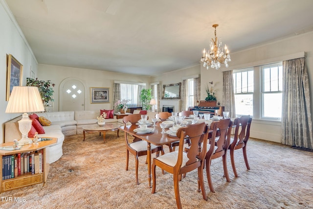 dining room with ornamental molding, a fireplace, and a chandelier