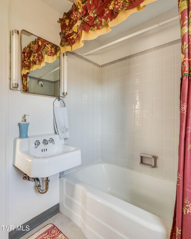 bathroom with shower / bath combo, speckled floor, and a sink