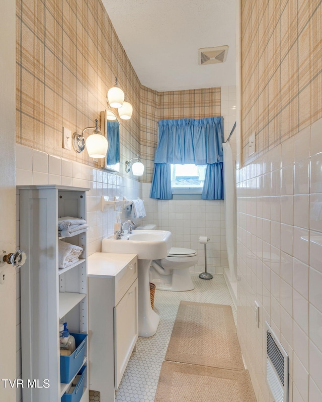 bathroom featuring tile patterned flooring, visible vents, heating unit, and tile walls