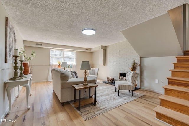 living area featuring light wood-style floors, stairs, visible vents, and a fireplace