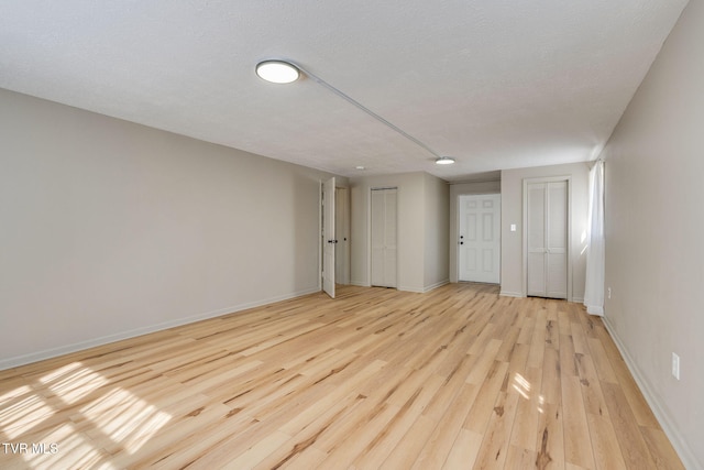 spare room featuring light wood-style floors and baseboards