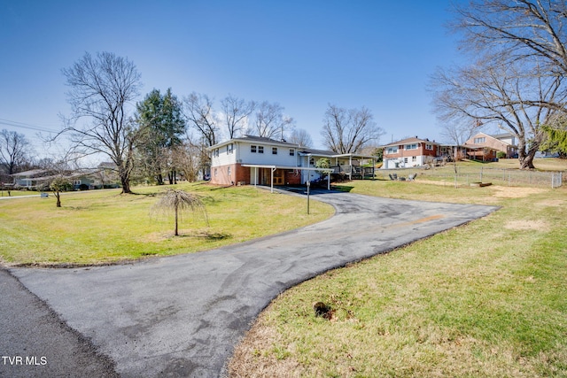 view of front of property with an attached garage, a front lawn, aphalt driveway, and brick siding