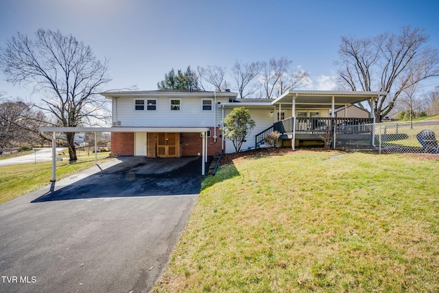 view of front facade featuring an attached carport, aphalt driveway, brick siding, fence, and a front lawn