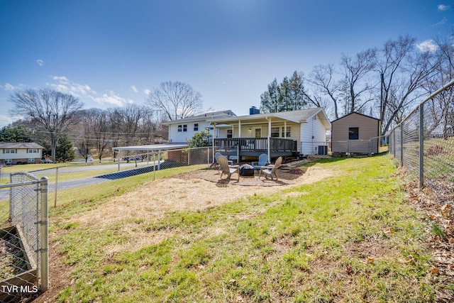 back of property with a yard, an outdoor fire pit, and fence