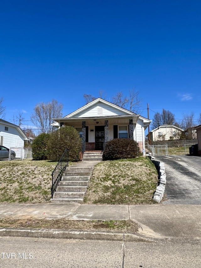 bungalow-style house with driveway, a porch, fence, and a gate