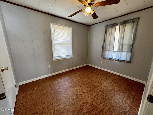 empty room featuring baseboards, a ceiling fan, crown molding, and wood finished floors