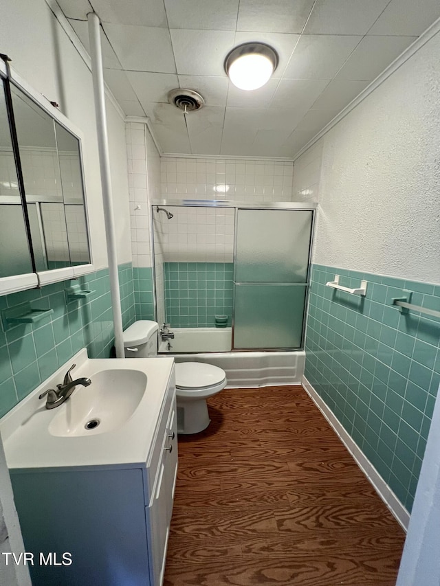 bathroom with shower / bath combination with glass door, tile walls, vanity, visible vents, and crown molding