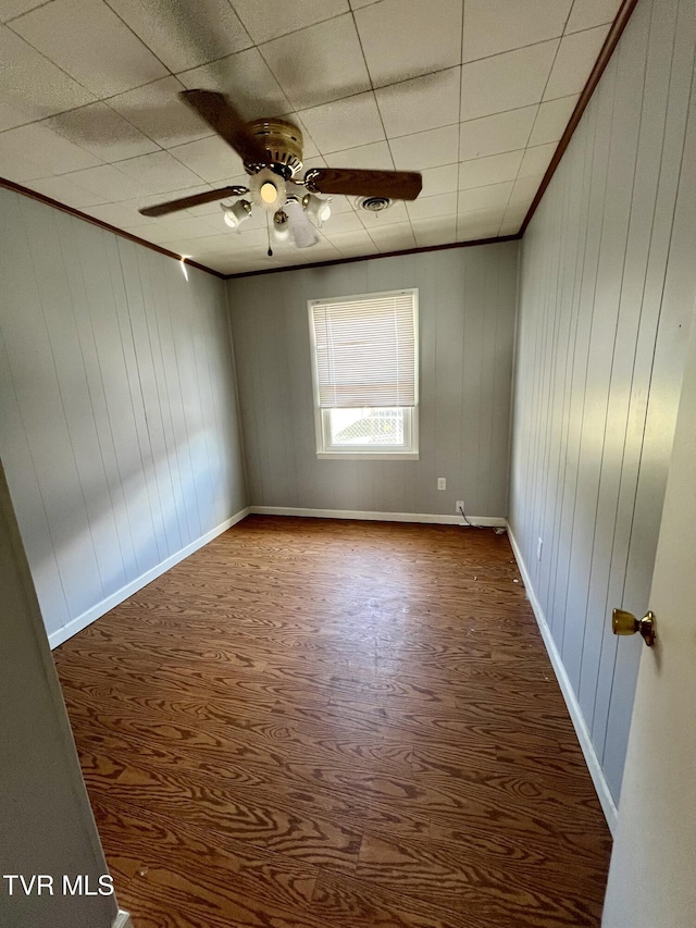 empty room with ornamental molding, a ceiling fan, and baseboards