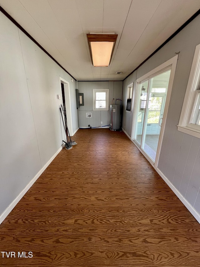 spare room featuring water heater, dark wood-type flooring, and baseboards