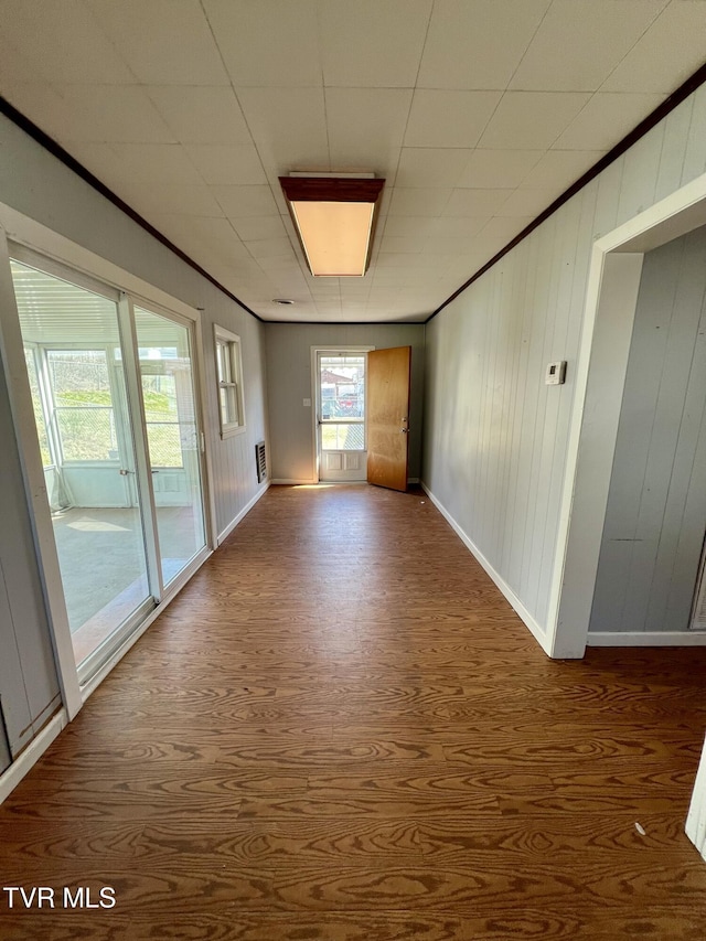 spare room featuring crown molding, wood finished floors, and a healthy amount of sunlight