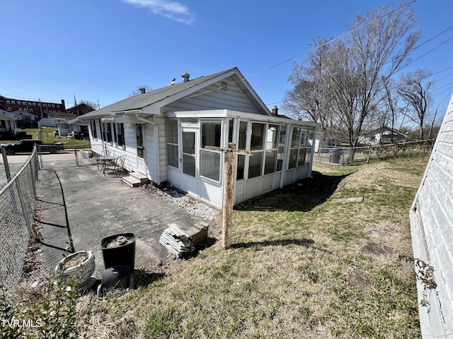 view of side of property featuring a lawn, a fenced backyard, and a sunroom