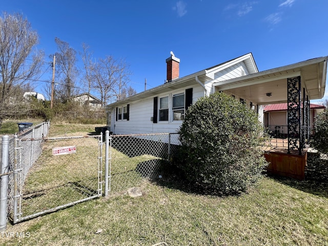 view of side of home with a yard, fence, and a chimney