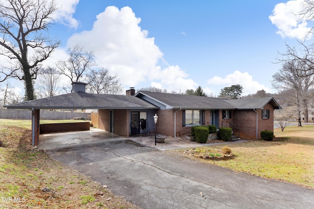 ranch-style house with driveway, a chimney, an attached carport, a front lawn, and brick siding