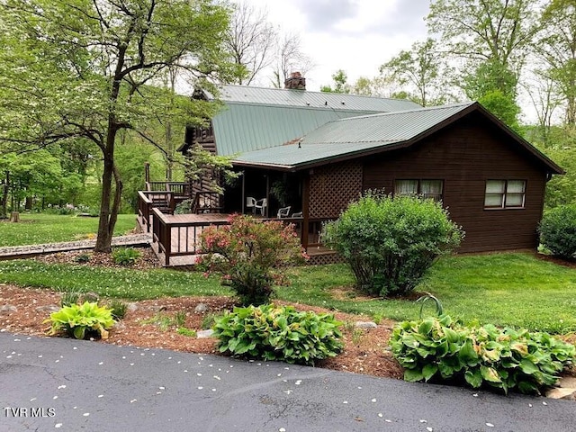 exterior space featuring a lawn, a chimney, a deck, and metal roof