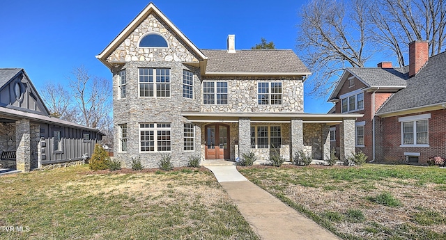 view of front of property with stone siding, covered porch, and a front lawn