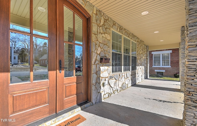 property entrance with a porch and stone siding