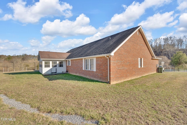 rear view of house featuring a yard and brick siding