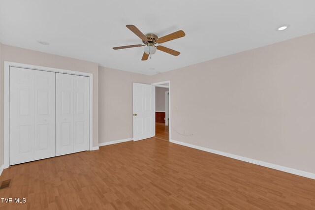 unfurnished bedroom with a closet, visible vents, a ceiling fan, light wood-type flooring, and baseboards