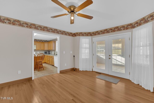 interior space with baseboards, ceiling fan, french doors, light wood-style floors, and a sink