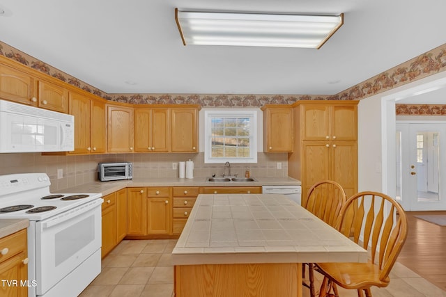 kitchen featuring white appliances, a toaster, tile counters, a kitchen island, and a sink