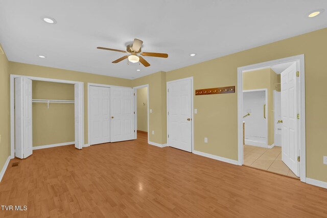 unfurnished bedroom featuring two closets, recessed lighting, ensuite bath, light wood-type flooring, and baseboards