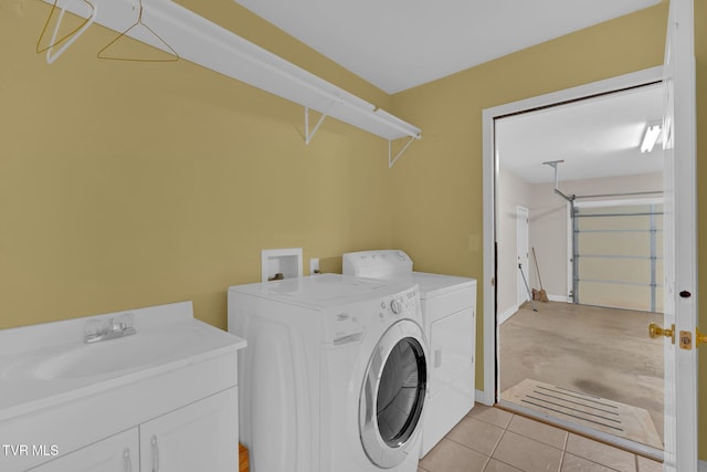 laundry room featuring light tile patterned floors, washing machine and dryer, a garage, laundry area, and a sink