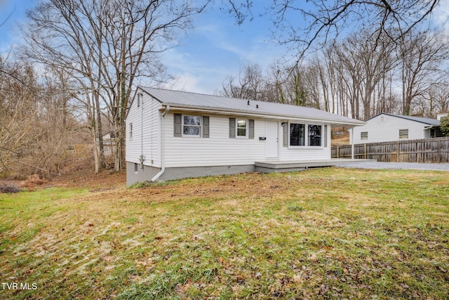 view of front of home featuring fence, metal roof, and a front yard