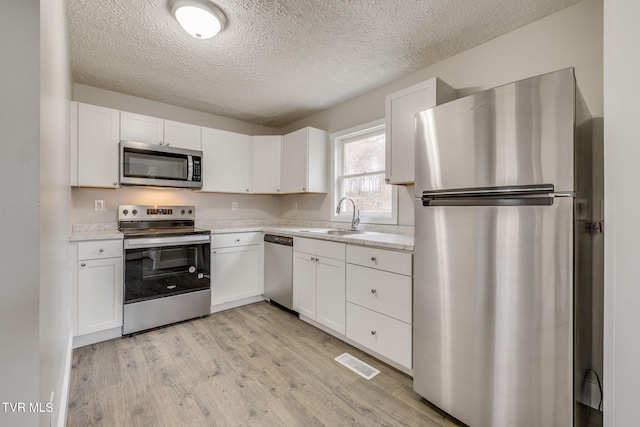 kitchen with light countertops, appliances with stainless steel finishes, a sink, and visible vents