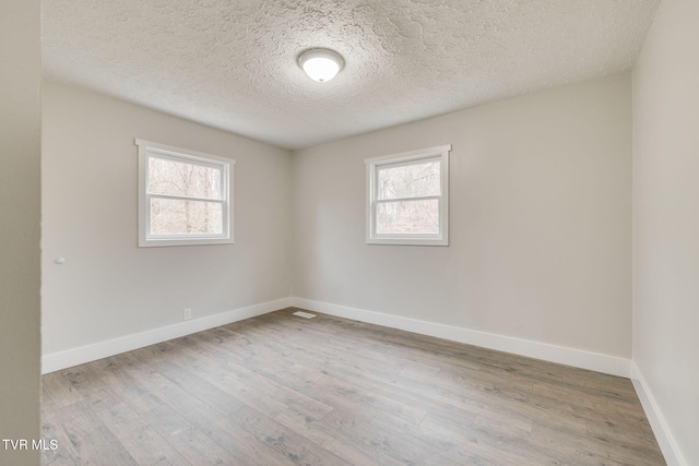 spare room featuring plenty of natural light, wood finished floors, and baseboards