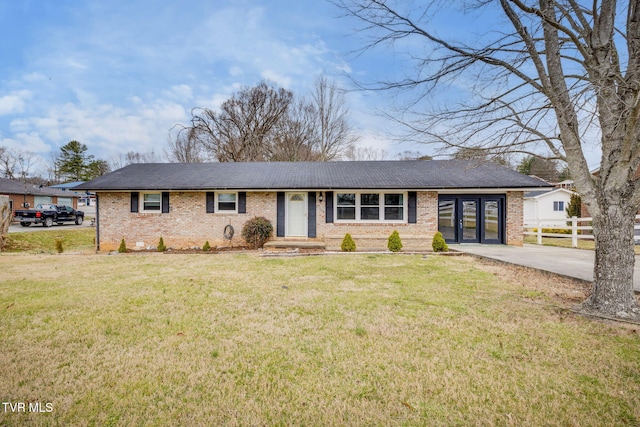 view of front of home with driveway, brick siding, fence, and a front yard