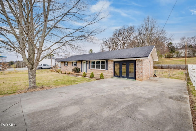 view of front of home featuring driveway, fence, french doors, a front yard, and brick siding