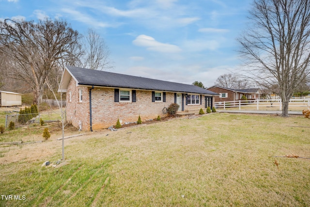 ranch-style home with brick siding, a front lawn, and fence