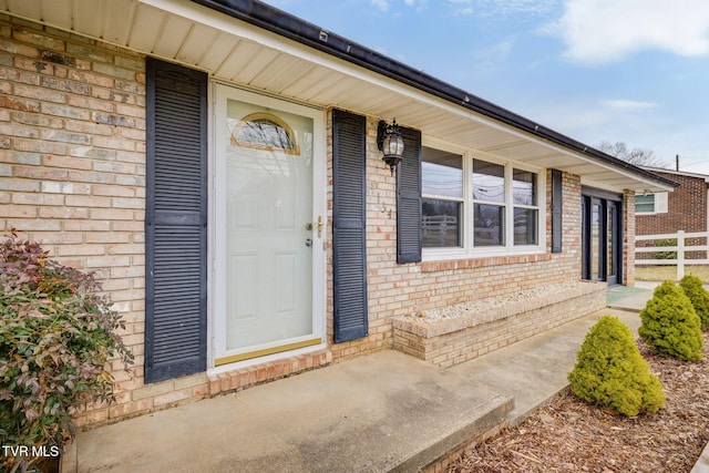 property entrance with fence and brick siding