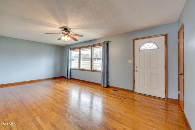 foyer entrance featuring baseboards, light wood-style flooring, visible vents, and a textured ceiling