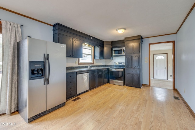 kitchen with visible vents, appliances with stainless steel finishes, light wood finished floors, dark countertops, and crown molding