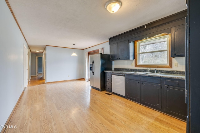 kitchen featuring light wood finished floors, dark countertops, appliances with stainless steel finishes, crown molding, and a sink