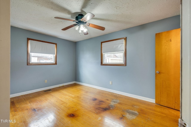 unfurnished room featuring a ceiling fan, light wood-style flooring, baseboards, and a textured ceiling