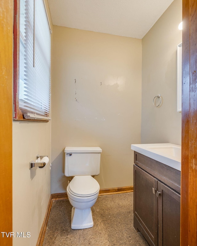 half bath with toilet, vanity, and baseboards