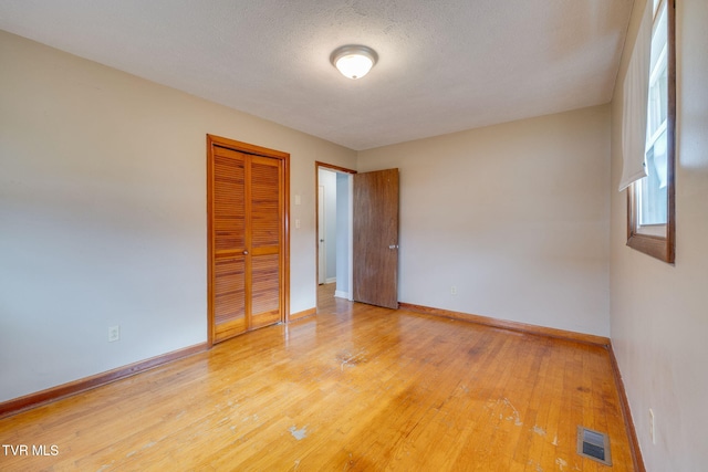 unfurnished room featuring baseboards, a textured ceiling, visible vents, and light wood-style floors