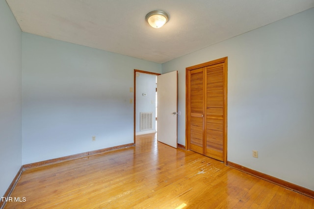 empty room with light wood-type flooring, visible vents, and baseboards