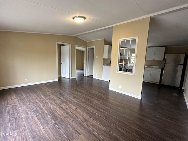 empty room featuring dark wood-style floors, lofted ceiling, crown molding, and baseboards